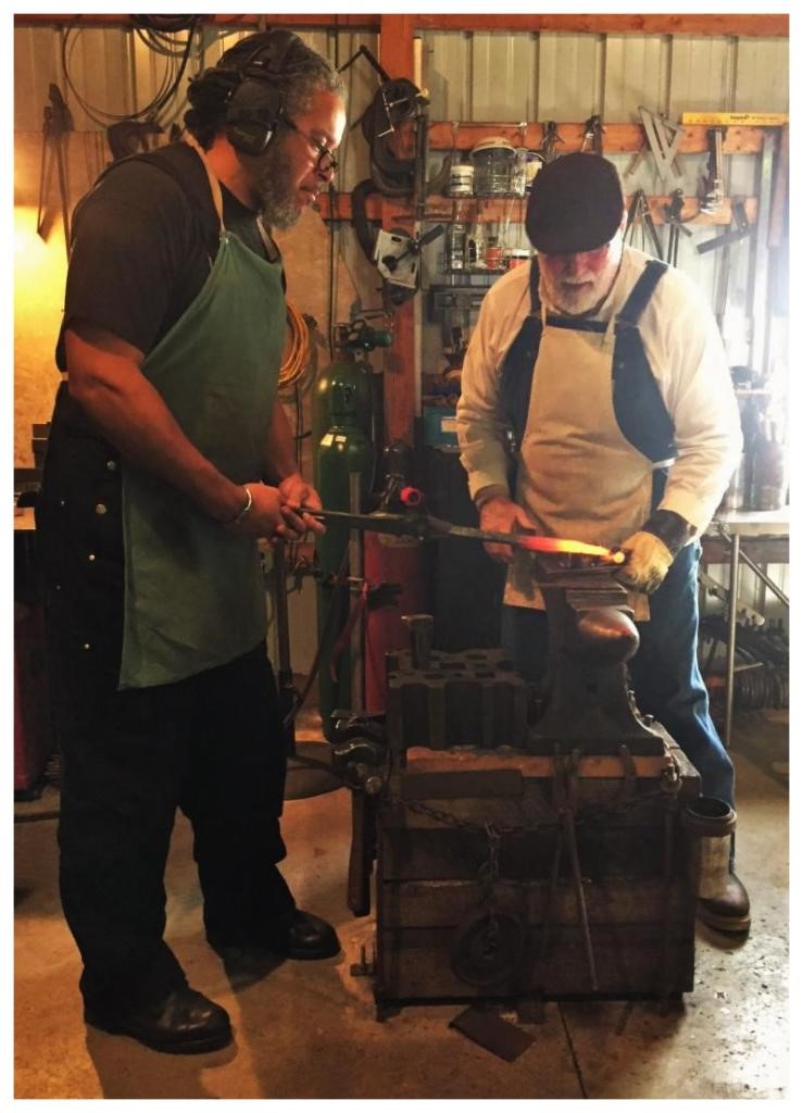 Blacksmith, Stephen Nuttall (left), assists Master Blacksmith, Toby Kroll, with forging a dragonfly.